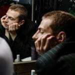 Mężczyzna w przebieralni patrzy w lustro, zastanawiając się nad sobą