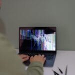 Osoba pracująca na laptopie z pękniętym ekranem w domu