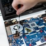 Ręka naprawiająca płytę główną laptopa śrubokrętem