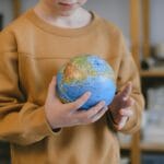 Dziecko trzymające globus, symbol podróży i nauki o świecie