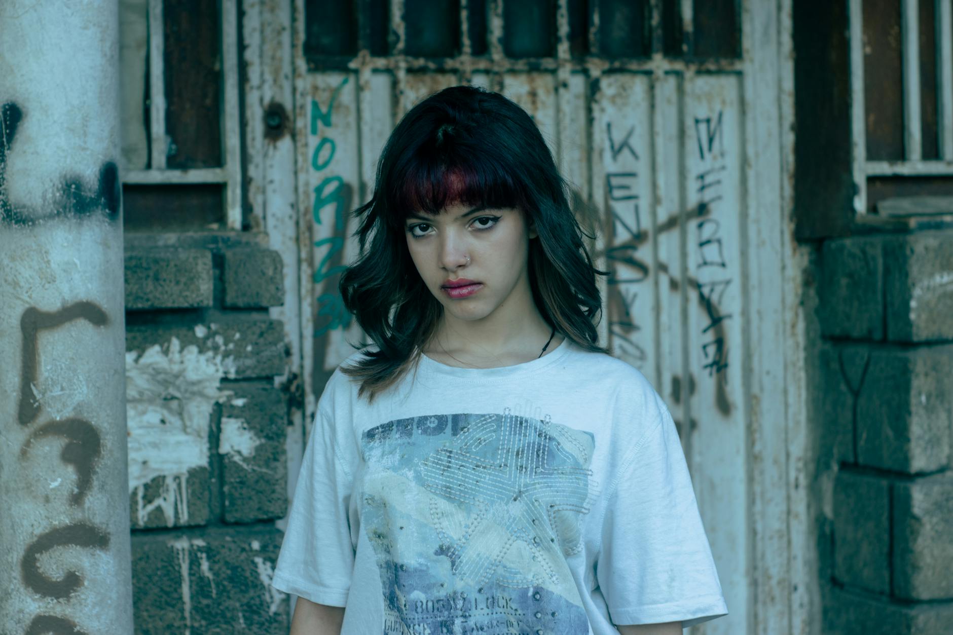 Młoda kobieta pewnie stoi na tle miejskiej ściany z graffiti