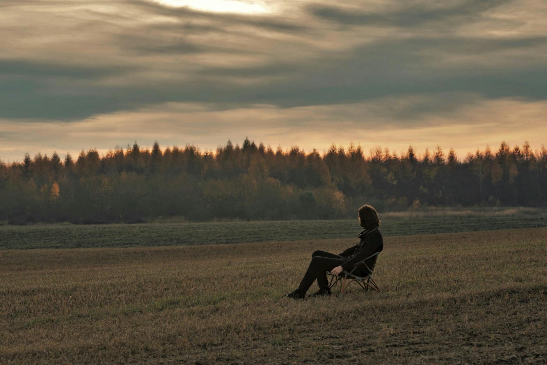 Samotny mężczyzna na krześle na polu o zachodzie słońca