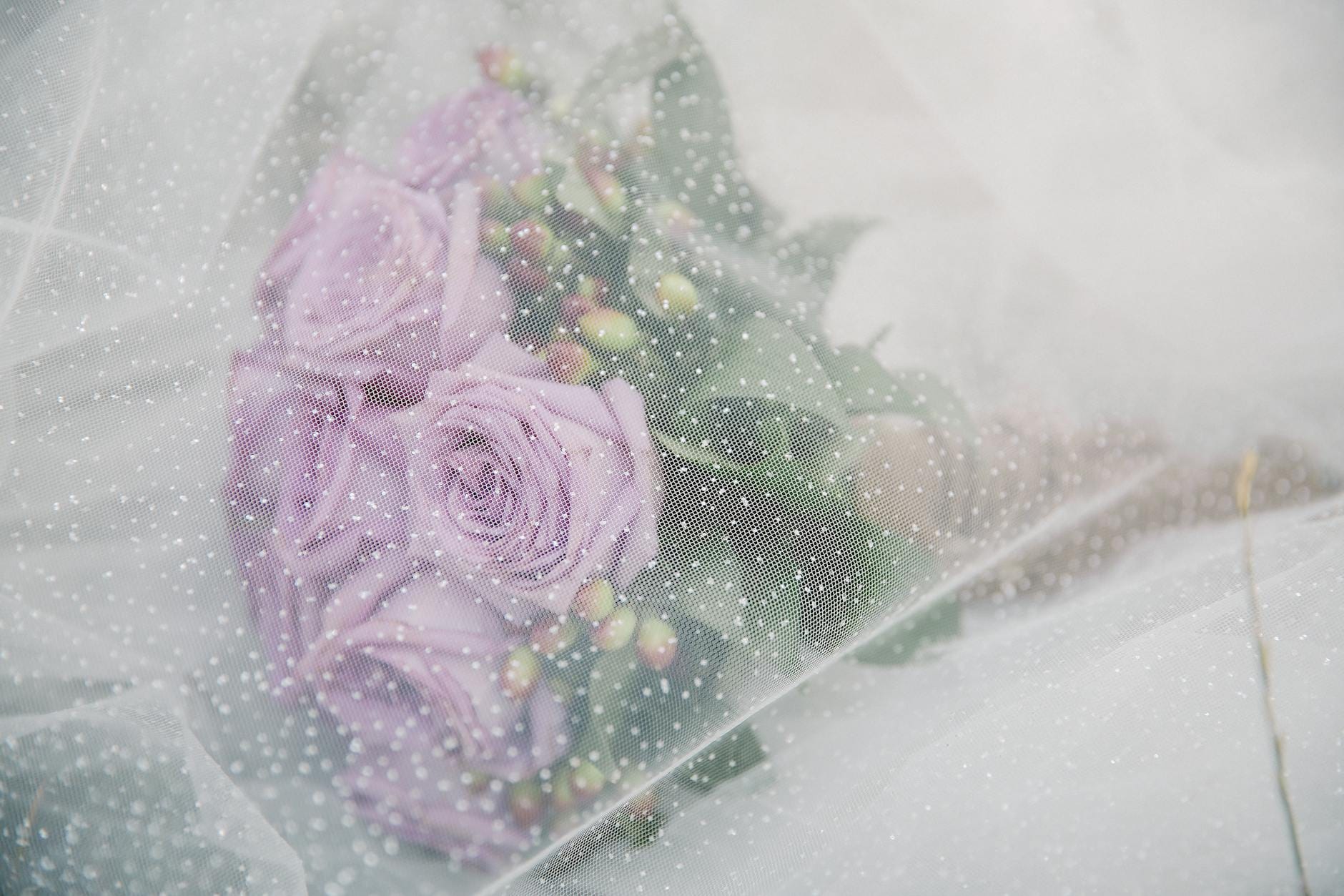 Delikatny ślubny bukiet z lawendowych róż pod tiulowym welonem