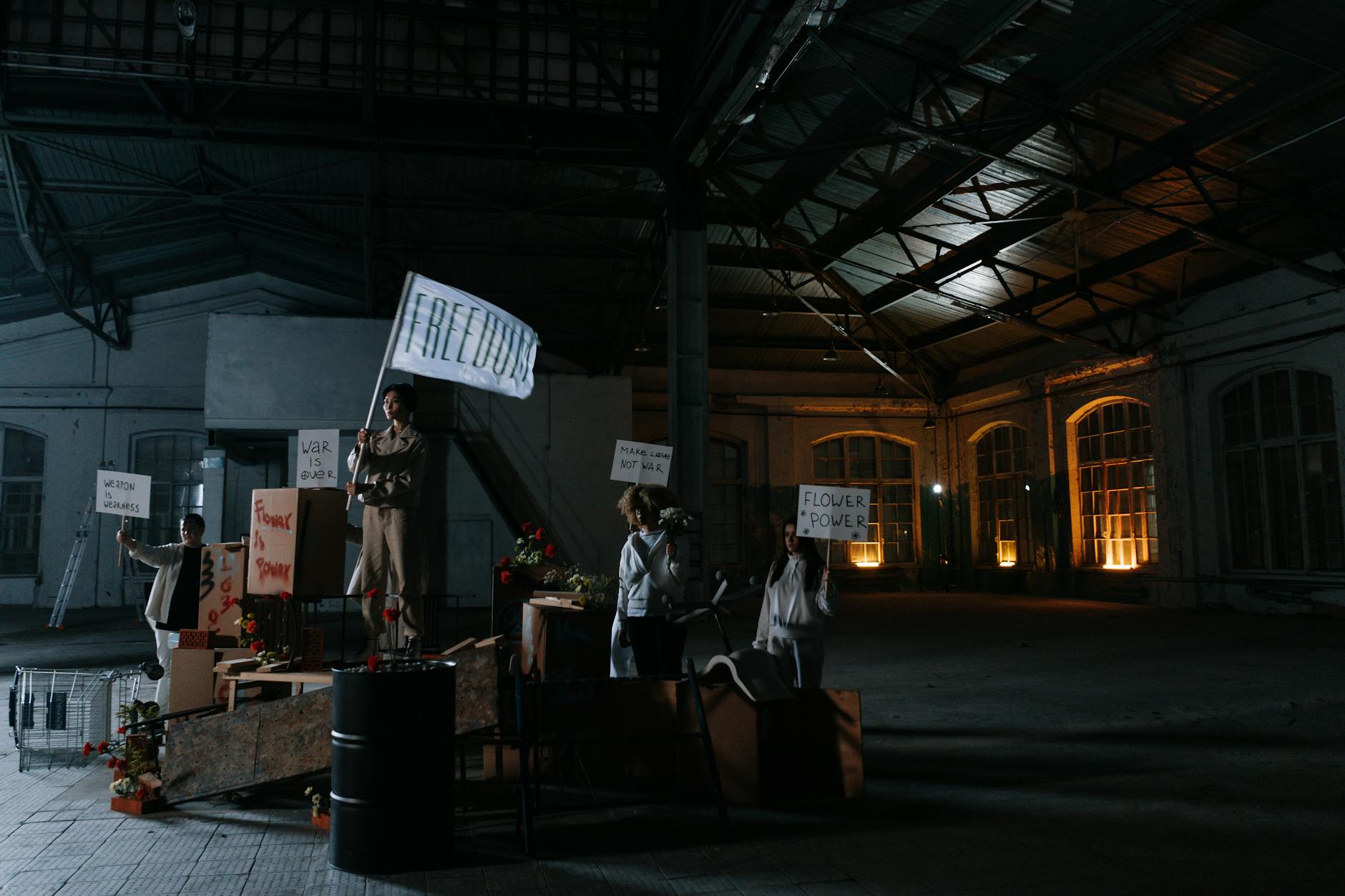 Grupa ludzi w pomieszczeniu trzyma transparenty i flagę wolności