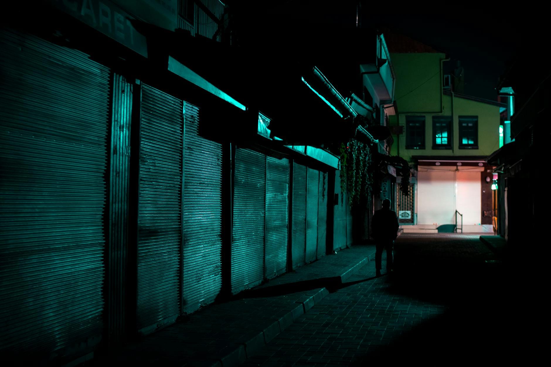 Sylwetka samotnej osoby w mrocznym, wąskim miejskim zaułku