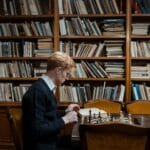 Mężczyzna zamyślony nad partią szachów w przytulnej bibliotece