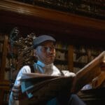 Zadumany mężczyzna czyta gazetę w bogato zdobionej bibliotece